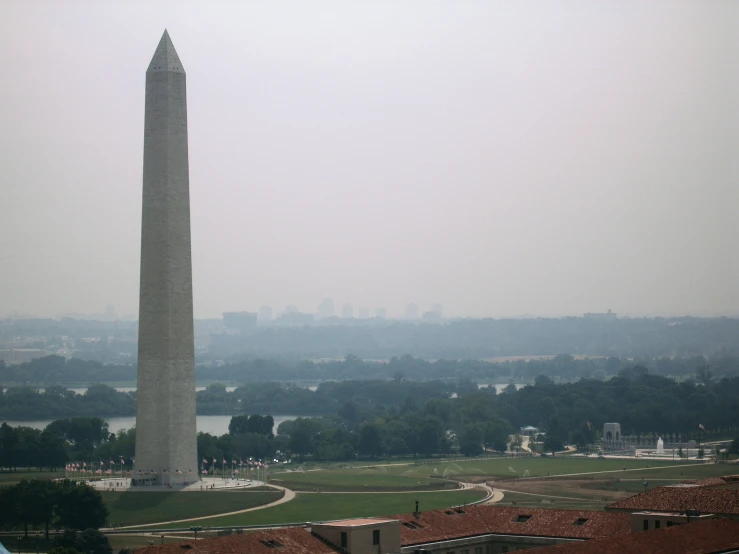 the washington monument is seen with red roofing in the foreground