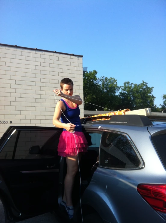 a young woman in blue dress standing next to car