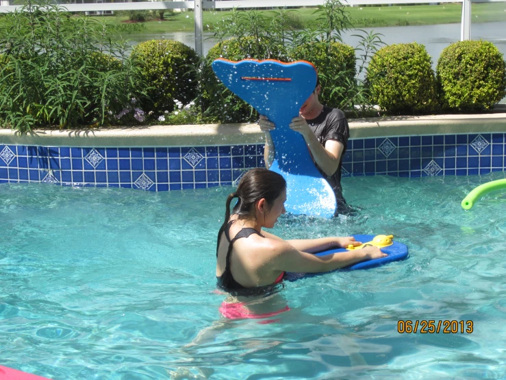 the woman is playing in the pool with the boogie board