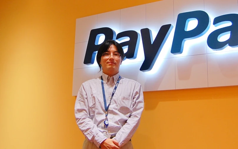 a man stands outside the paypass store with a sign behind him