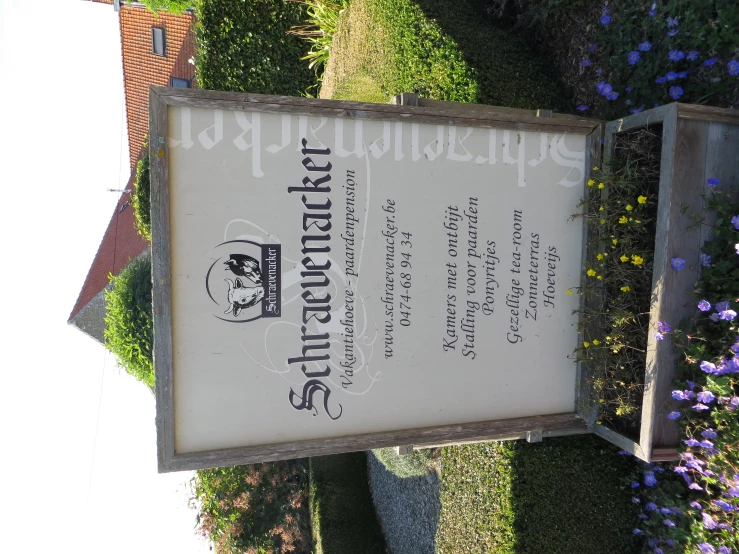 a sign in front of a garden with lots of flowers