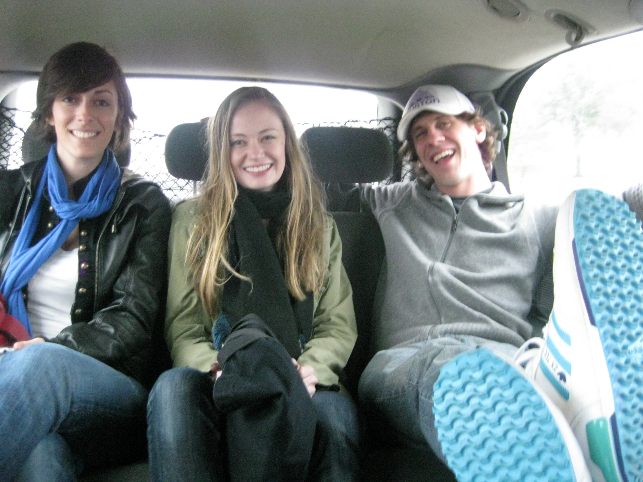 three people sitting together in the back seat of a vehicle