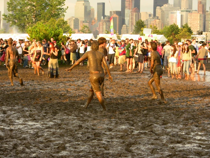 people standing in mud with a cityscape in the background