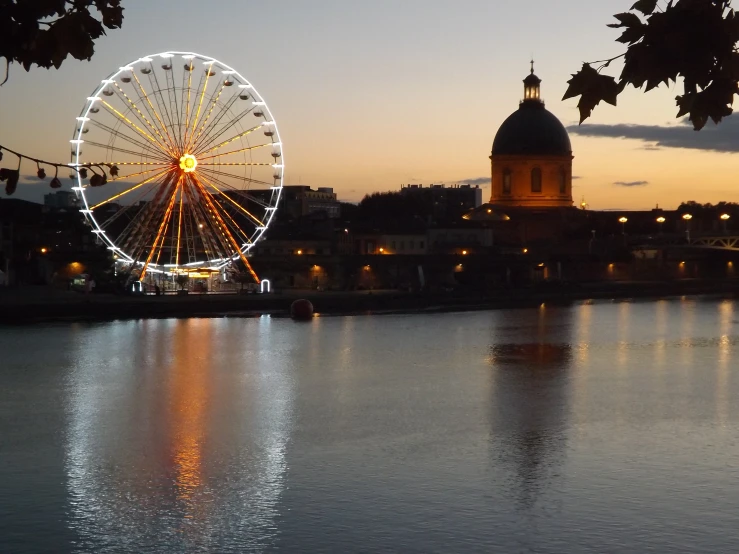 a ferris wheel in the city on the side of the water