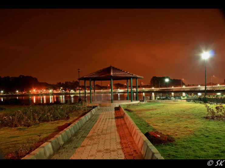 a lit walkway and an empty gazebo at night