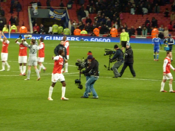 a soccer team is walking on the field with cameras