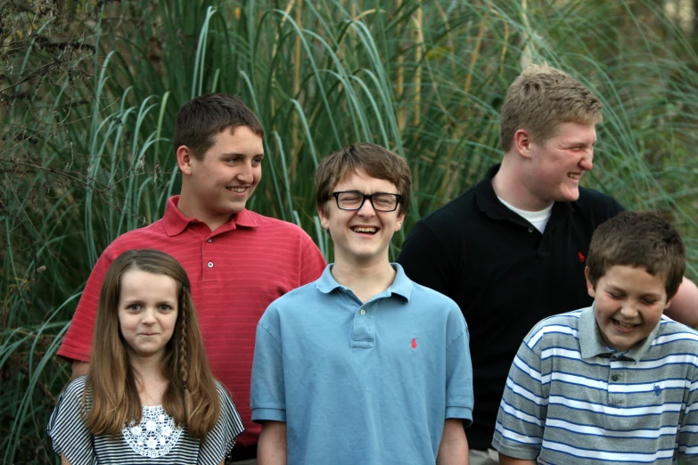 four people standing in front of some tall grass