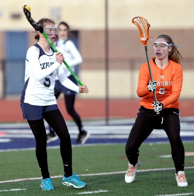 two girls are playing lacrosse on the field