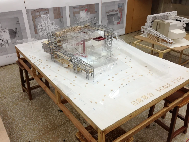 an architectural model sits on a table in front of some drawing