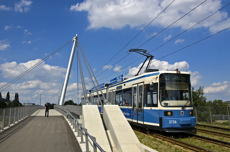 a blue tram going over a bridge on tracks