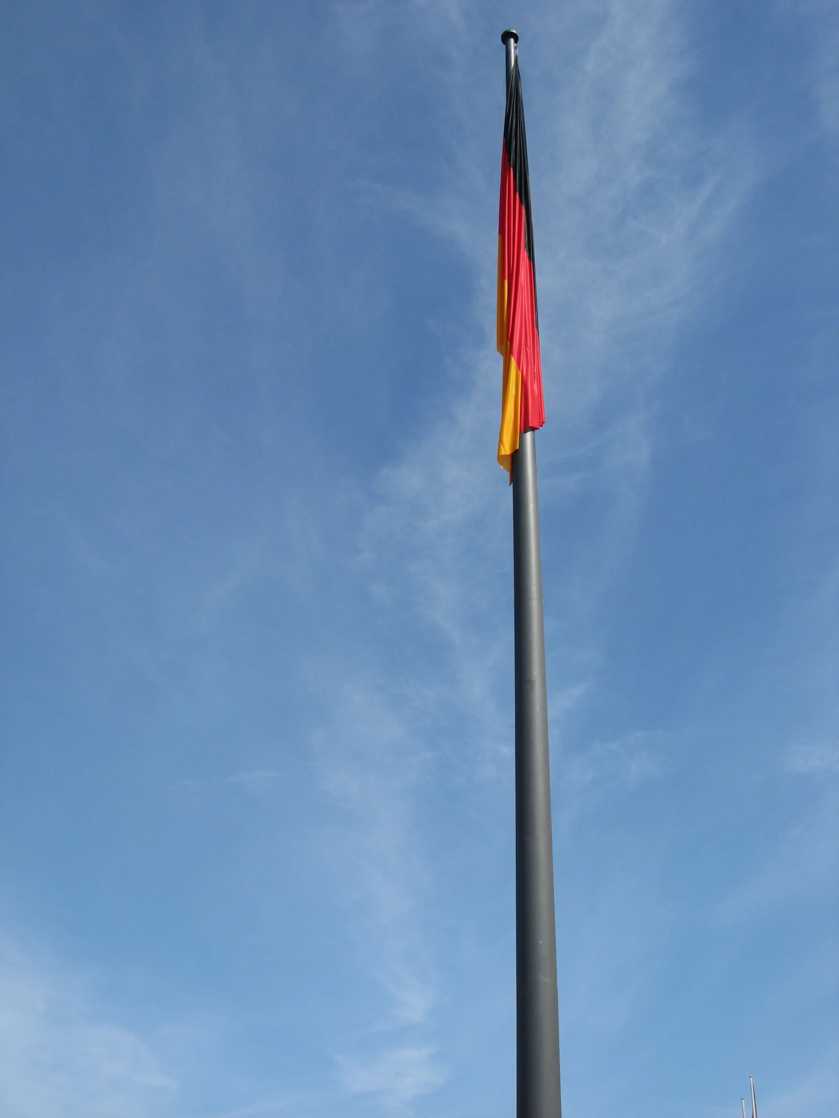 a flag flies high in the blue sky near a large pole