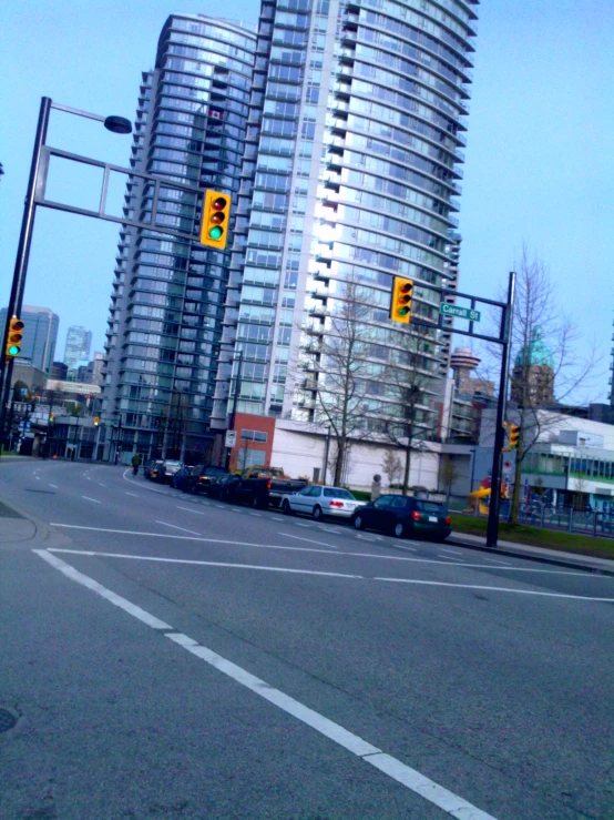 some cars stopped at an intersection in front of high rise buildings