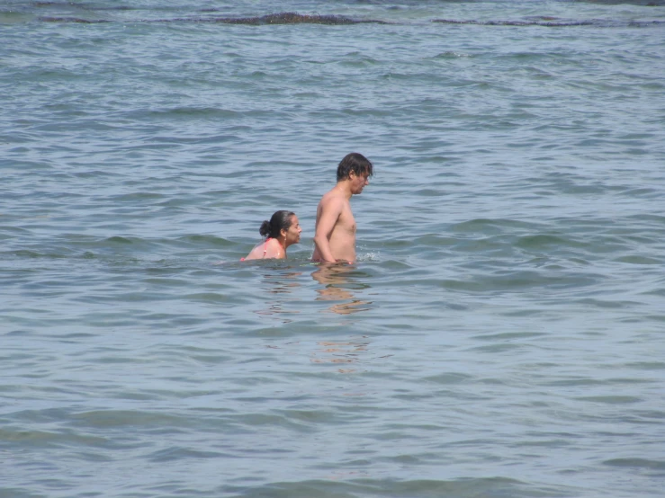 a girl and boy swimming in the ocean with their heads touching each other