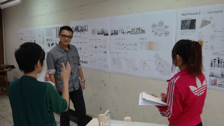 four young people standing by a board discussing a project