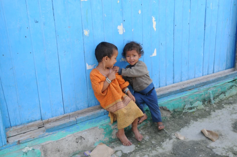 two young children standing by a blue painted wall