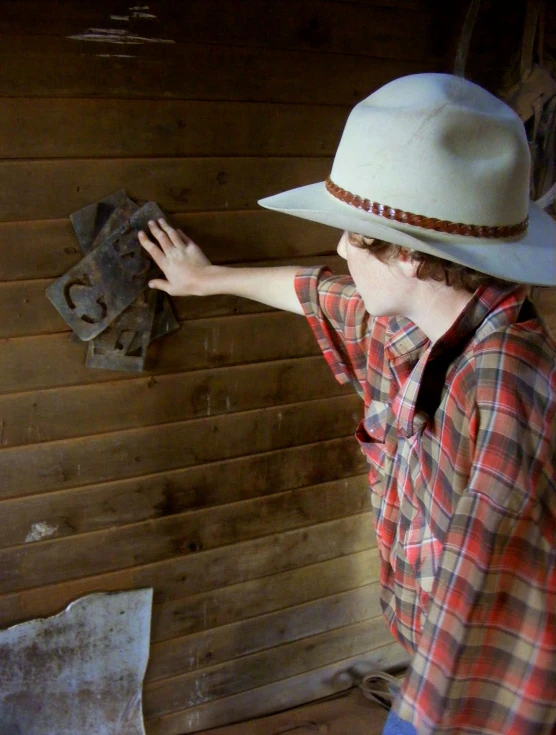 man wearing a cowboy hat looks at some type of metal item