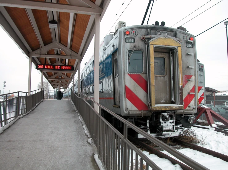 an empty train station in the snow with a train on the tracks