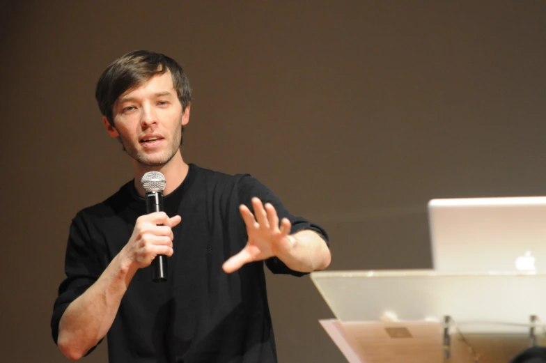 man holding microphone in front of large screen