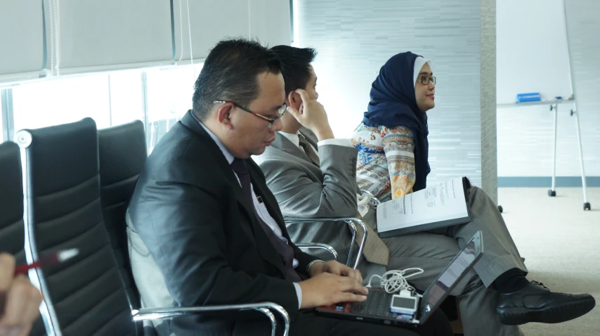 four business men sitting down using their computers