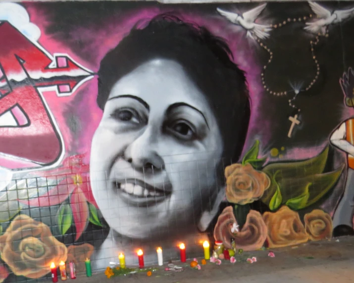 a wall with some candles near it, and a picture of a woman