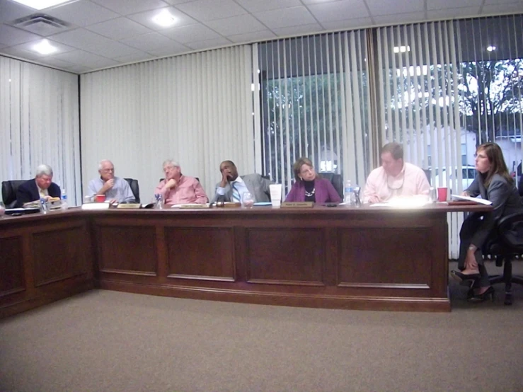 people sitting at a conference room table in front of large windows