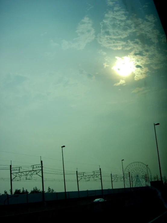 the sun shines behind a ferris wheel