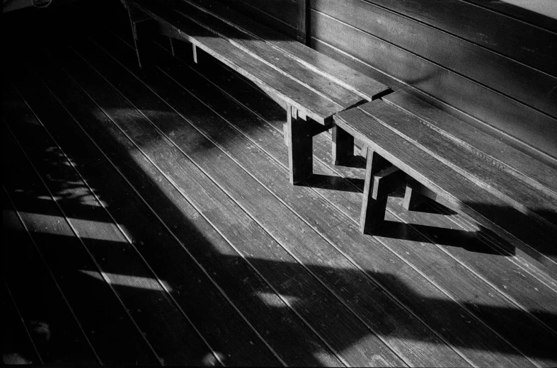 two benches sit against the wood surface of a porch