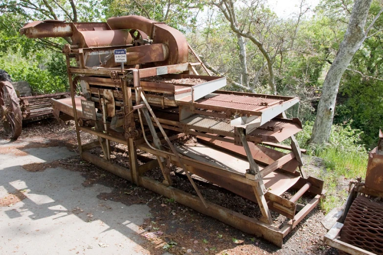 an old wooden mill machine is outside in the woods