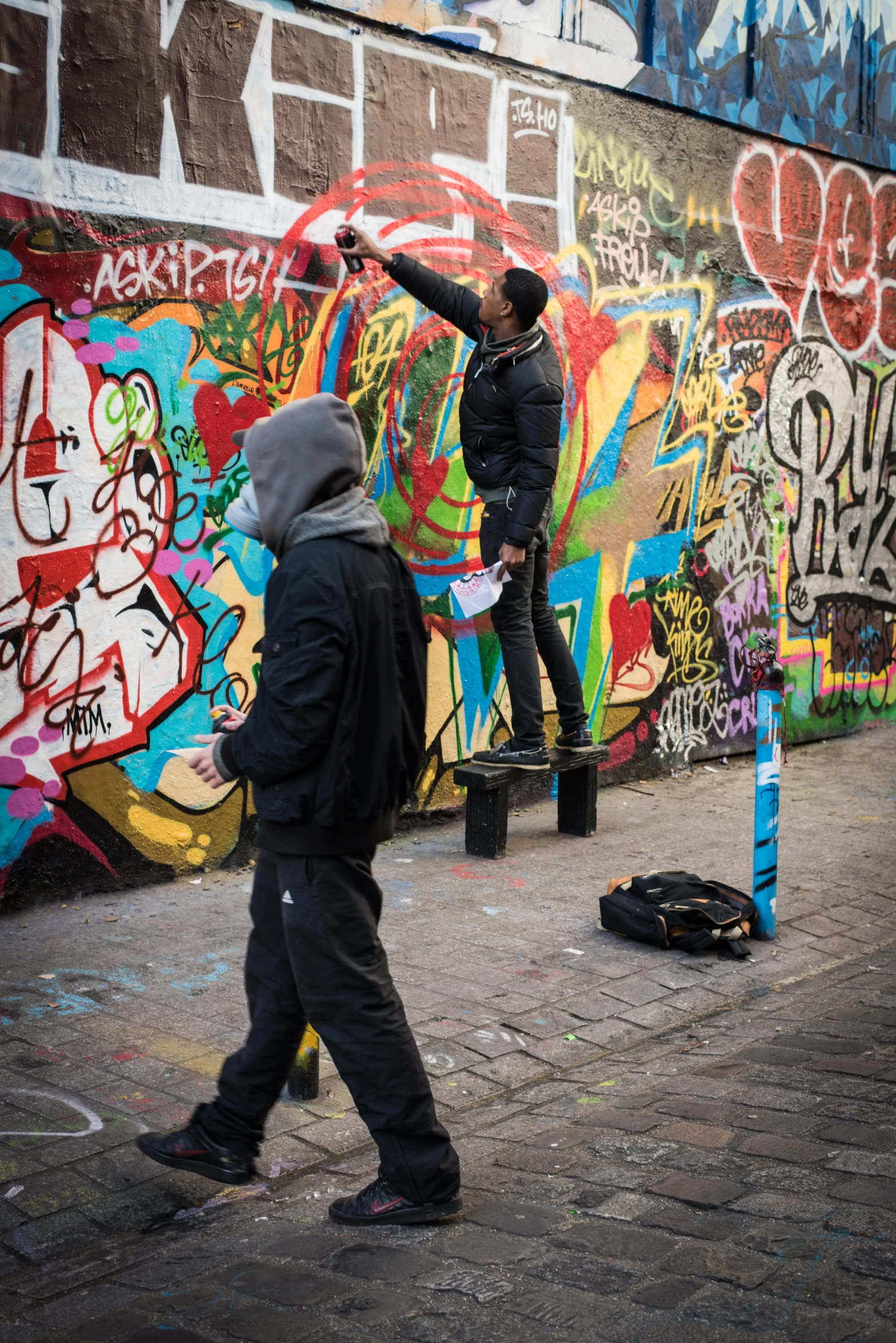 a man is painting a wall covered with graffiti