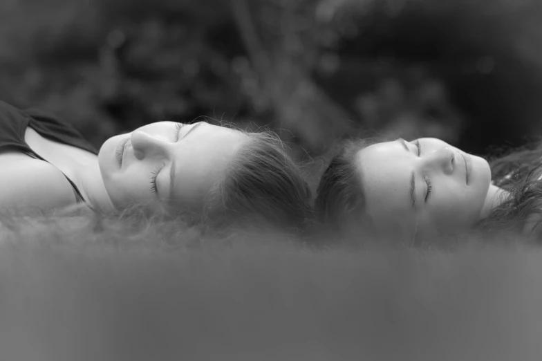 two women are laying on their side in the grass