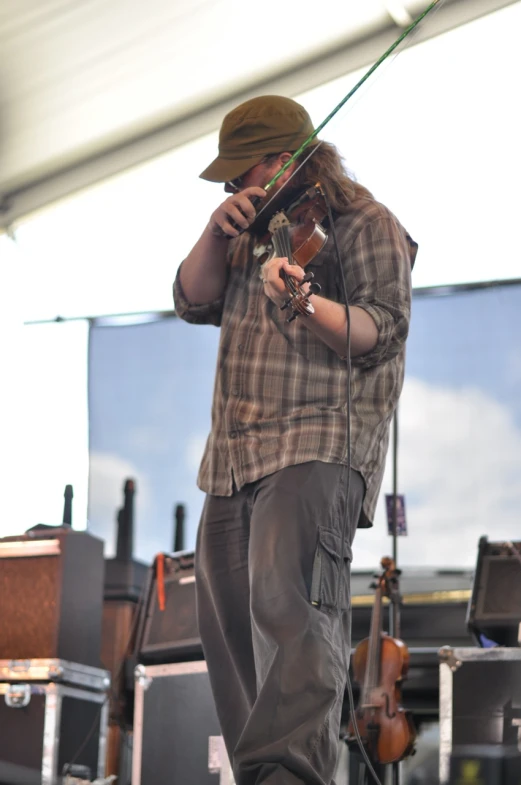 a man in plaid shirt playing on violin in front of an audience
