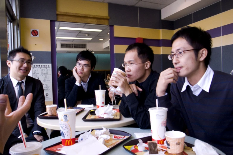 some asian men sit at a diner eating together