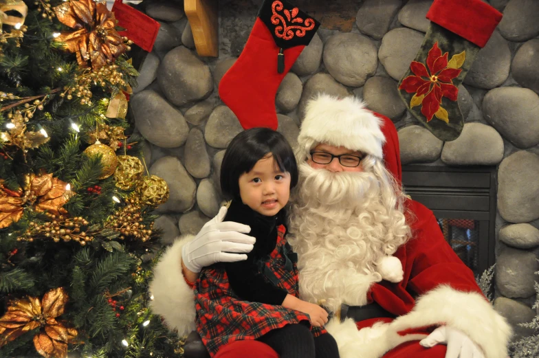 a little girl sitting next to a santa clause