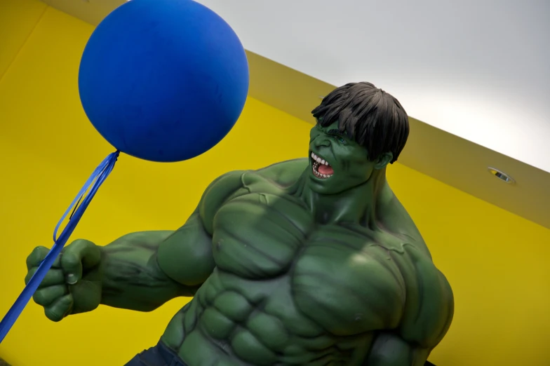 a large hulk figure is holding a blue balloon