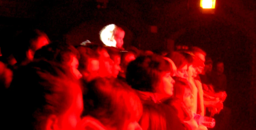 people standing in front of a red light at a concert