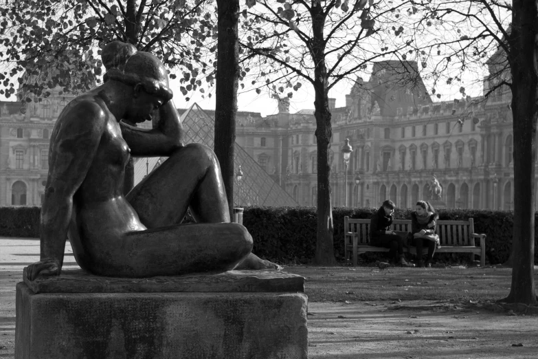 a statue sitting in a park near trees