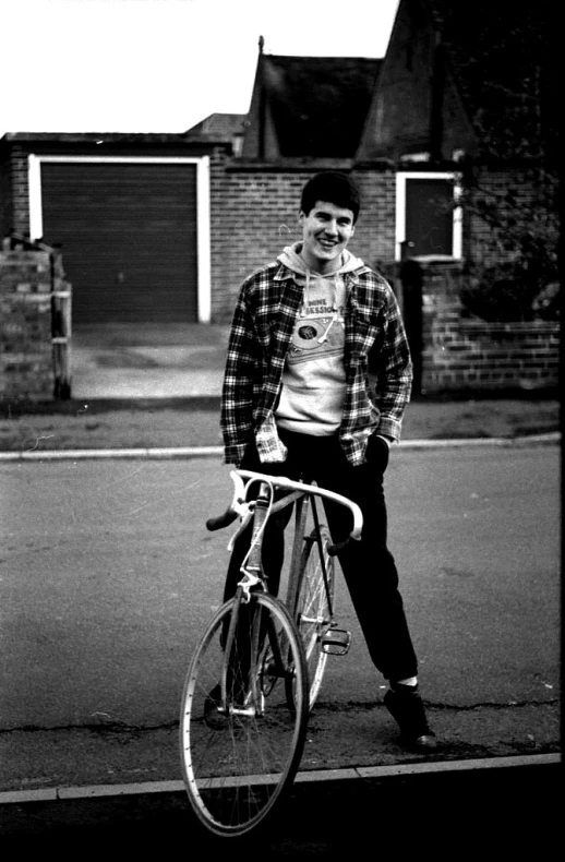 a young man holding onto his bike while smiling