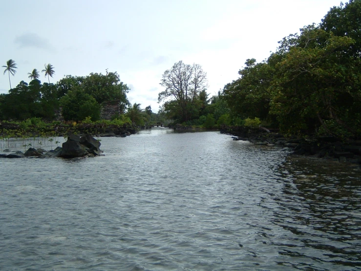 a waterway with large rocks, trees, and water