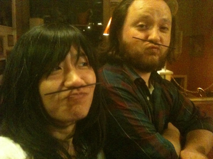 man and woman with large piercings sit on a couch