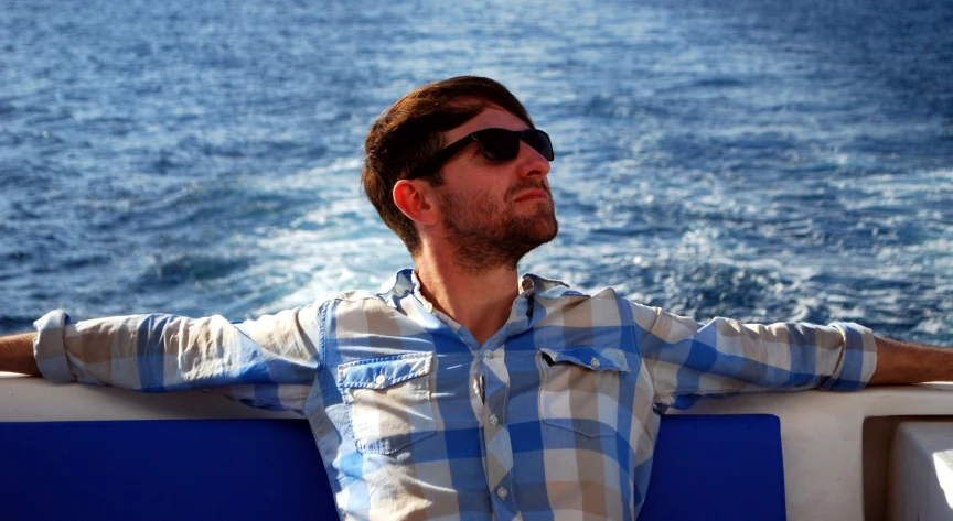 man sitting on top of a boat looking at the water