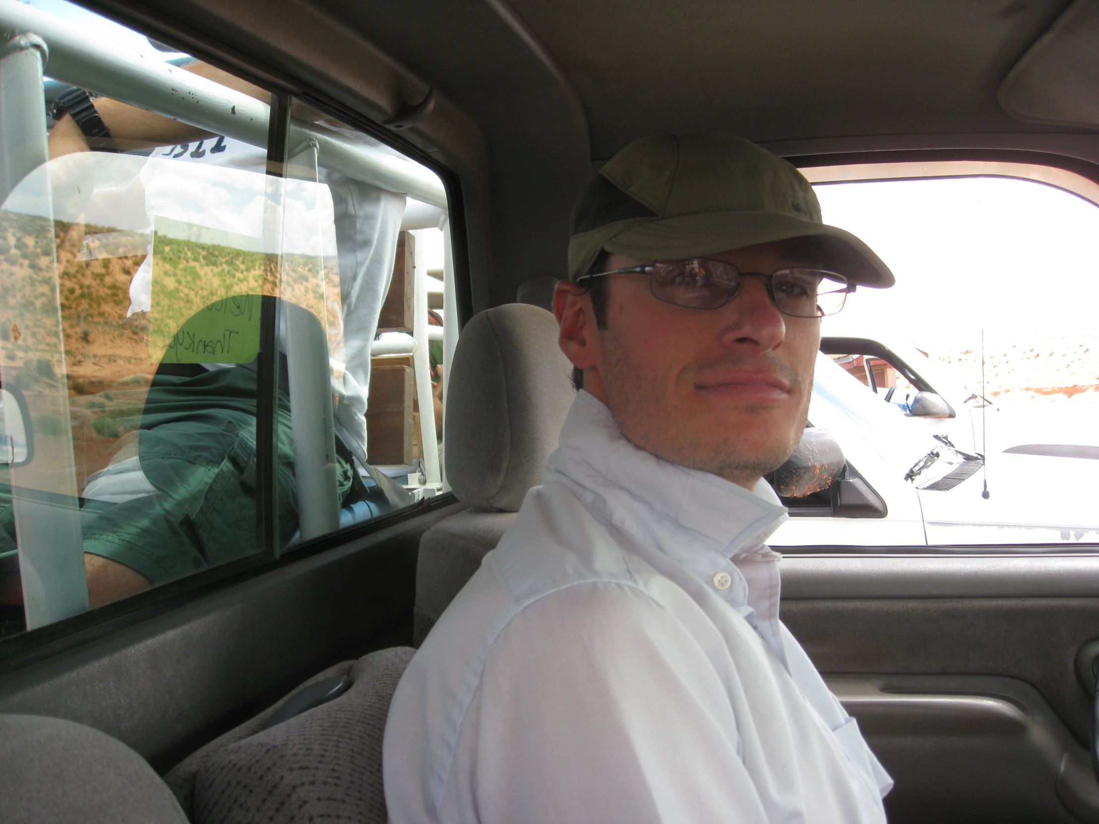 a man with a hat sitting inside of a car