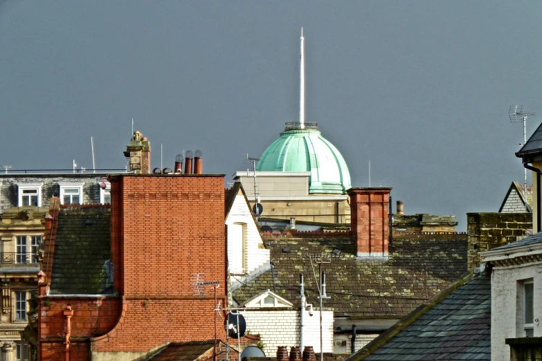 the rooftops of several buildings with a green dome in the background