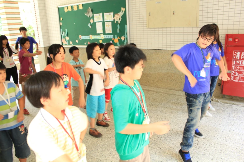 many young children stand and sing in front of a man