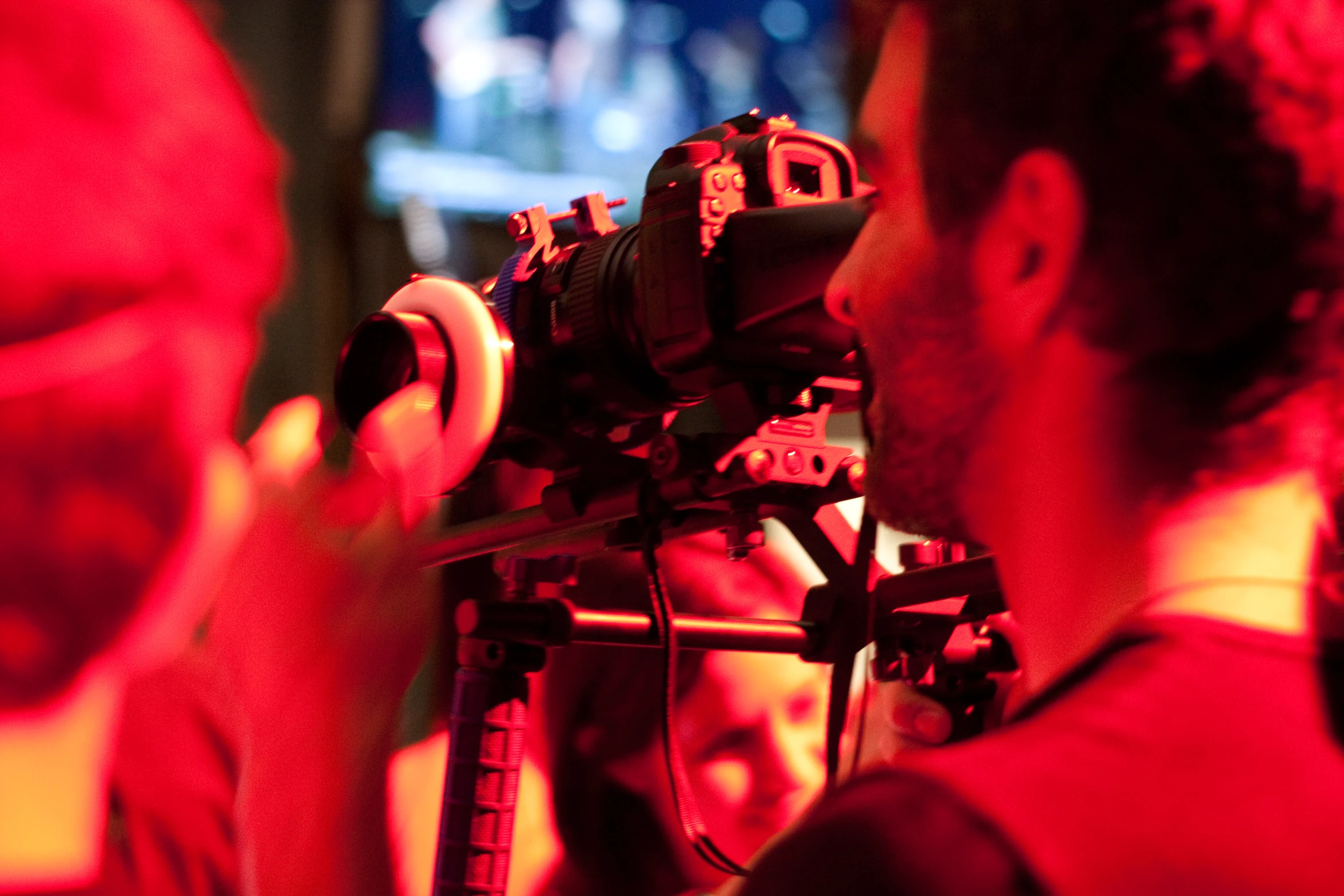 two men in front of a camera with red light