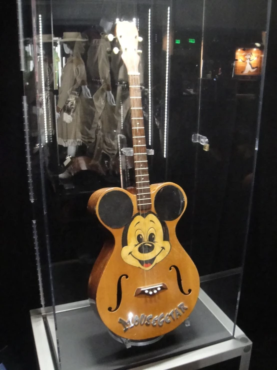 an antique mickey mouse guitar sits in a glass case