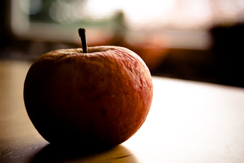 an apple sits on a table next to the window