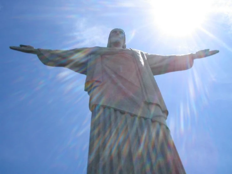 the statue of jesus in the sun is against a blue sky