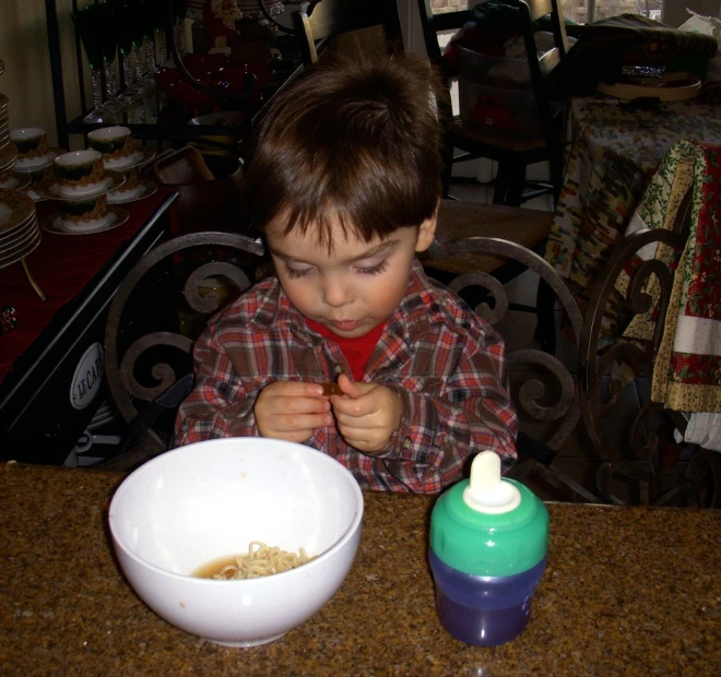 a boy sitting at a table eating cereal