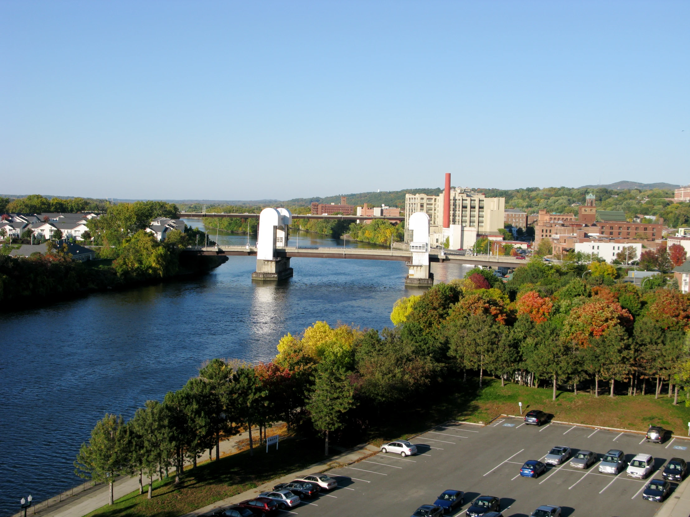 the town of a city with cars parked on a lot next to a river