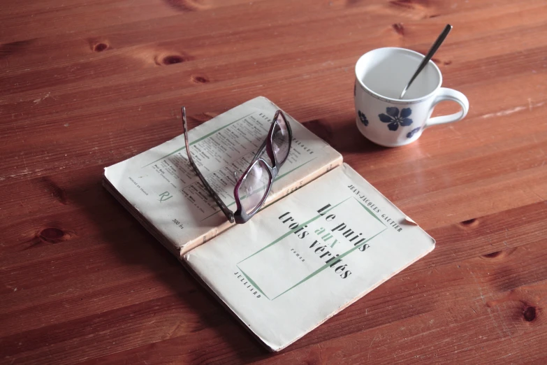 glasses and newspaper with cup on wooden table